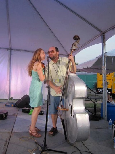 With metal upright bass and fiddle, Casey & Minna sing into the same mic on stage at the Paseo Festival in Oklahoma City. 