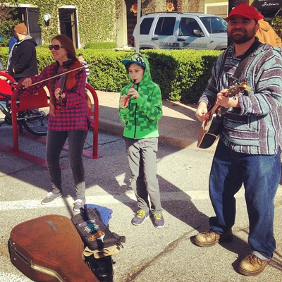 On a chilly April morning on the opening day of the Cherry Street Farmers Market in Tulsa Oklahoma Casey, Minna and August Biggs play music on fiddle, guitar, and tin whistle. Ten year old August looks quit cold; he tries to conserve heat nestled in his bright green hoody. 